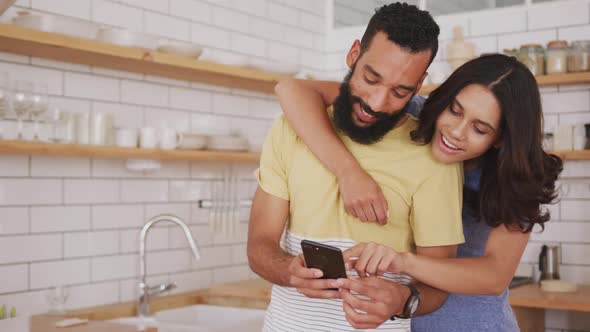 Happy couple looking at each other while using smartphone