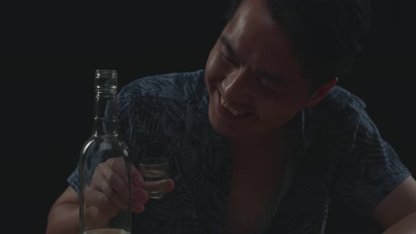 Close Up Of Drunk Asian Man Cheering Vodka With Bottle Glass Before Drinking In Black Background