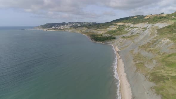 Backtracking aerial of Charmouth beach looking west along to Lyme Regis. Home of the UK fossil hunti