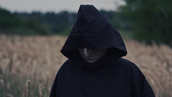 Ghost in black cloak walking in. Ghostly figure in field