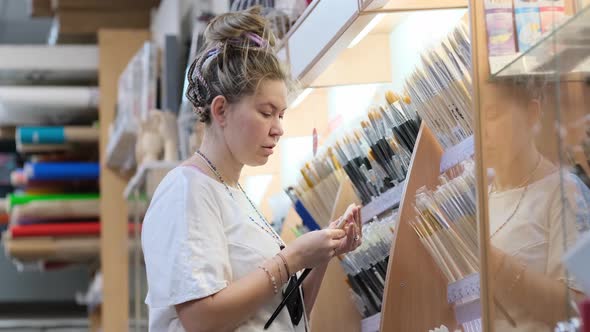 Woman Choosing Brushes for Drawing in Art Shop