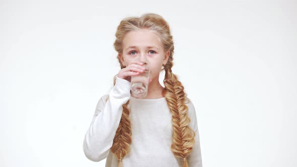 Cute Beautiful Caucasian Girl with Luxurious Blonde Hair Drinking Water Standing on White Background