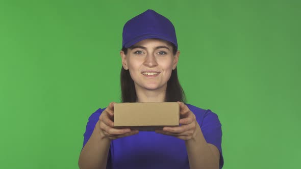 Happy Delivery Woman Smiling Holding Out Small Package To the Camera