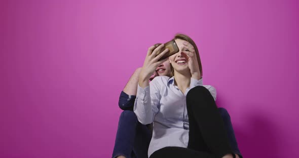 Couple Taking Selfie Over Pink Background