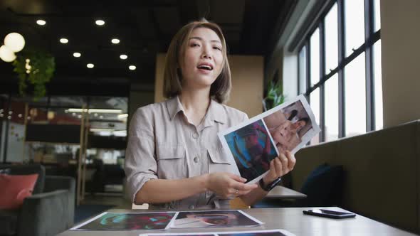 Asian businesswoman having a video chat going through paperwork modern office