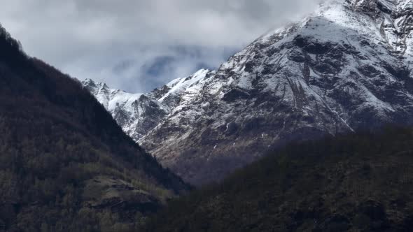 Majestic icy Italian alp mountain ridge with dark valley in foreground; parallax