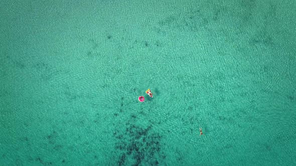 Aerial view of two young girls swimming and playing in sea with inflatables.