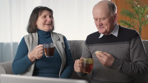 Joyful Wife and Her Loving Husband Have Fun and Laugh While Having Tea in Living Room