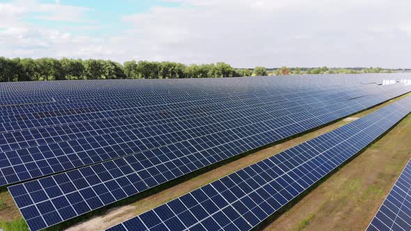 Aerial View of Solar Power Station. Panels Stand in a Row on Green Field. Summer