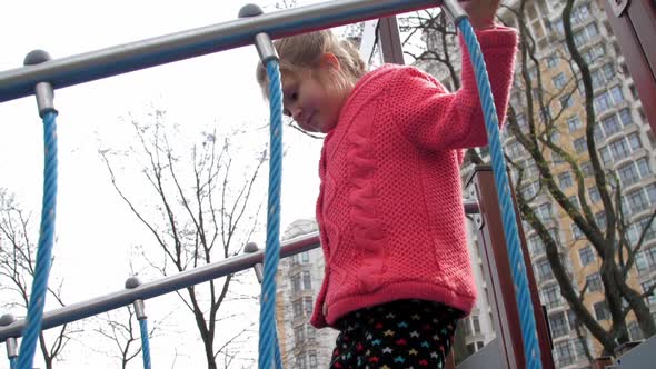 Concentrated Schoolgirl Walks Along Bridge with Ropes