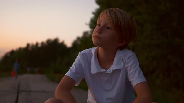 Closeup of a Blond Guy Sitting in a Park at Sunset