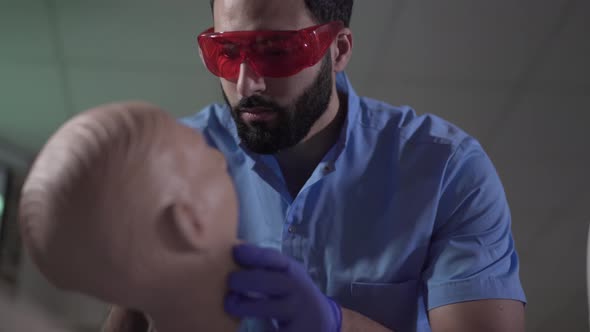 Close-up of Concentrated Middle Eastern Male Stomatologist Practicing with Dental Mannequin