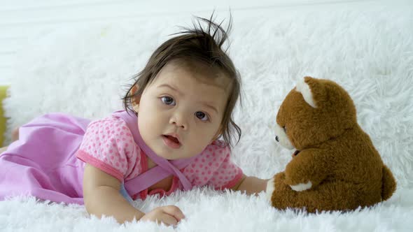 Cute cheerful girl baby toddler crawl to teddy bears to play and hug happily, rest and peace.