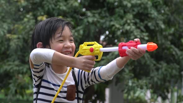 Cute Asian Child Playing With Water Gun In The Summer