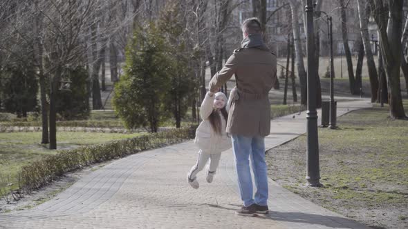 Wide Shot of Young Happy Father and Little Daughter Having Fun in Park on Sunny Day. Caucasian Man