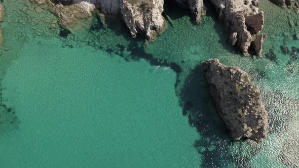 Two people swimming in crystal- clear, turquoise blue Mediterranean waters. Holdiay getaway shot. Su