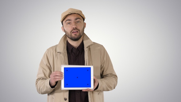 Man in Trench Walking and Holding Tablet with Blue Screen