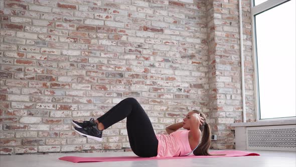 Young Beautiful Woman Does Crunches in the Gym