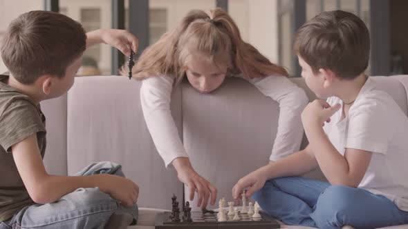 Kids Playing Chess Sitting on the Couch at Home. Siblings Spending Time Indoors. Happy Family