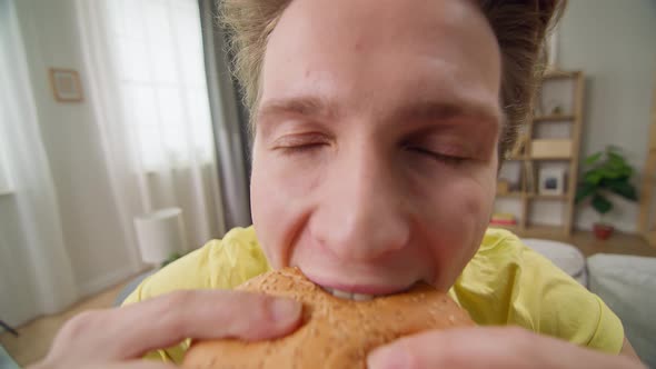 Young Man Bites Fun at the Burger in the Living Room