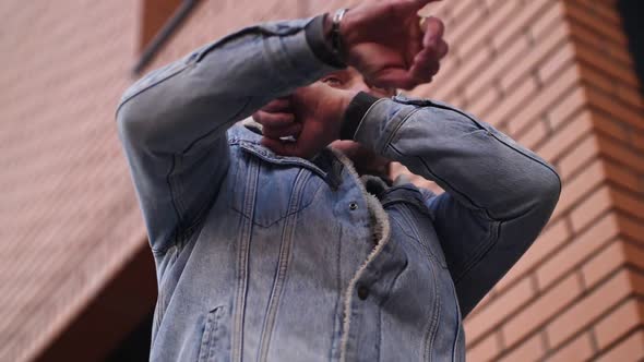 A Man Dances Against the Backdrop of a Kerpic Building