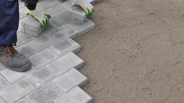 A Craftsman Lays Concrete Paving Stone Blocks on Sand