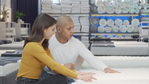 Happy Couple Examining Orthopedic Mattress on Sale at Furnishings Store