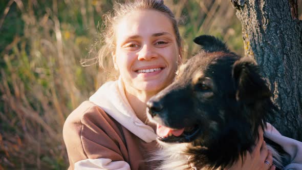 Portrait of a Young Woman Stroking Her Cute Shaggy Dog and Looking to the Camera