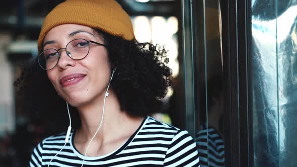 Smiling woman wearing hat listening music in headphones