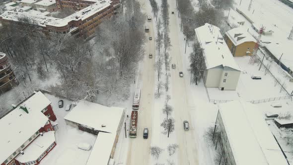 Cars on a City Straight Road Covered with Thick White Snow After a Blizzard