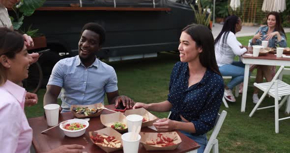 Multiracial friends eating at food truck table outdoor - Summer and lifestyle concept