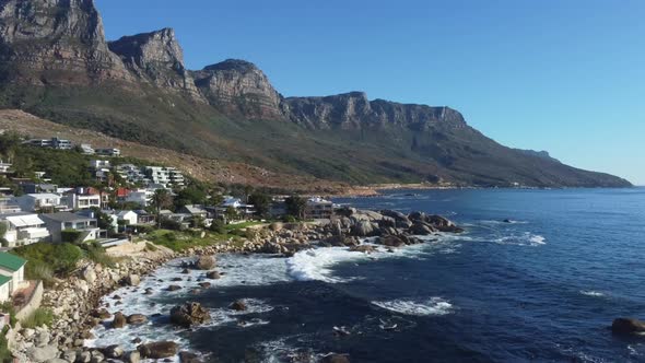 Drone shot of Bakoven beach in Camps Bay, Cape Town - drone is ascending facing nice beach villas. S