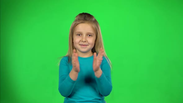 Little Girl Claps Her Hands and Have Fun on Green Background