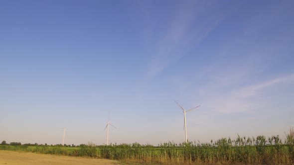 Group of Windmills for Electric Power Production in the Field at Sunset