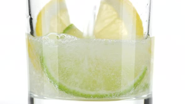 pouring water in glass with lime and lemon. Refreshing drink, sparkling water