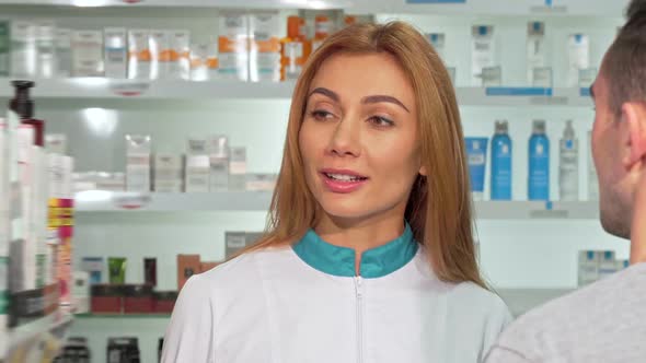 Friendly Female Pharmacist Helping a Customer at the Drugstore