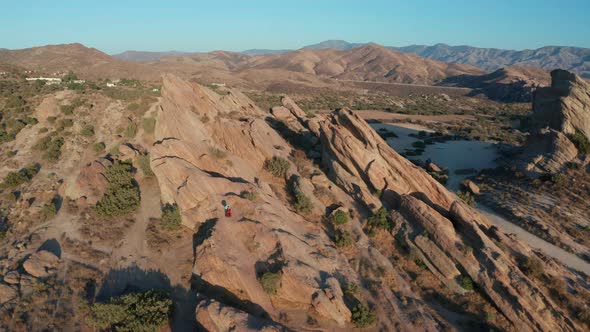 Aerial footage of mountains and dry land with blue cloudy sky in the background. 