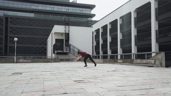 Young Female Gymnast Doing a Series of Flips on Training Area Near Modern Buildings