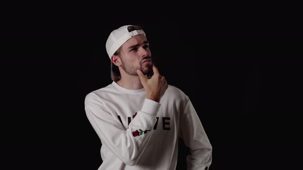 Trendy 20s Man rubbing chin and reflecting, wide, black background