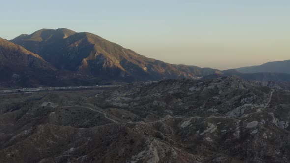 AERIAL: Over California Countryside with Highway and Mountains at Sunset 