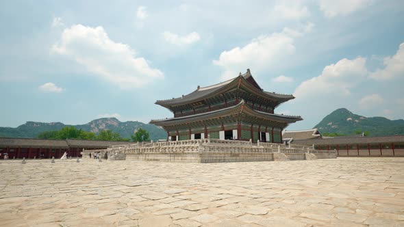 Gyeongbokgung Palace against Bukhansan mountains and floating fluffy clouds - wide static shot