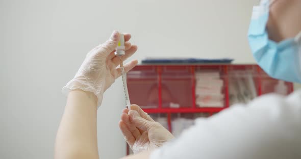 Medical with Face Mask Filling a Syringe with Vaccine