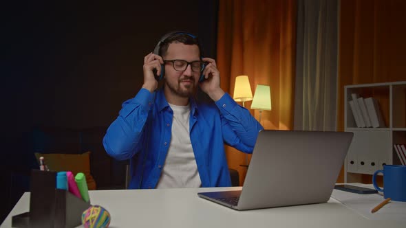 Relaxed Businessman in Glasses Wearing Headset Enjoying Listening Favorite Audio While Working