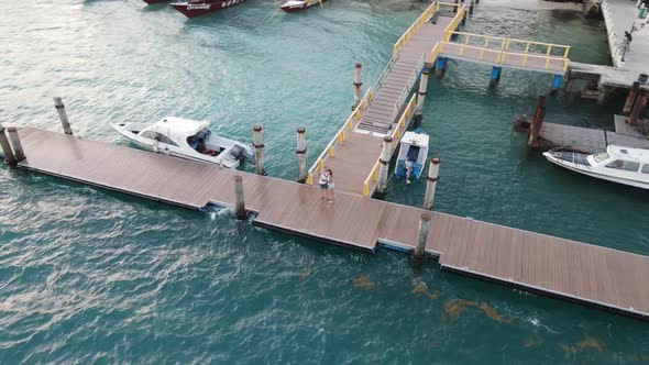 Sweet couple hugging on pier at harbor of Gili Air Island during holidays.Aerial circling shot.