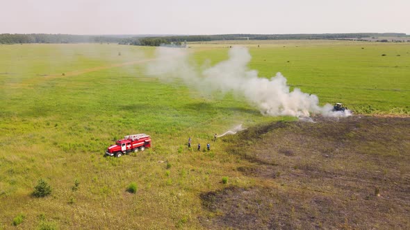 At the Edge of a Burning Field a Fire Engine and Firefighters