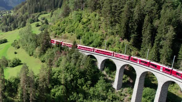 Aerial View of a Moving Red Train Along the Landwasser Viaduct in Swiss Alps