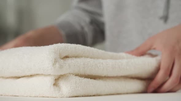 Young Woman Putting Washed Dry Clean Towels on Iron Board Preparing for Ironing