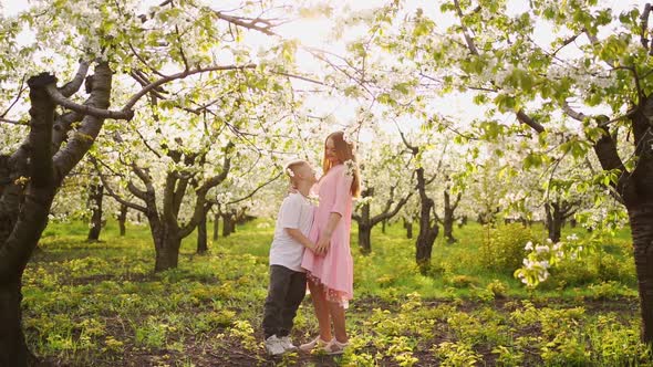 Mother and Son Teenager in a Flowering Spring Cherry Orchard