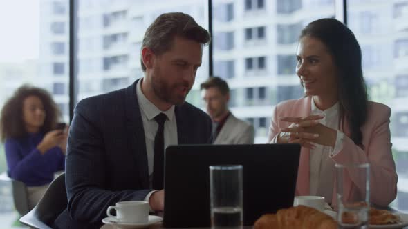 Cheerful Business Team Discussing Corporate Data Using Laptop Computer in Cafe