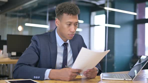 Attractive Young Businessman Reading Documents in Office